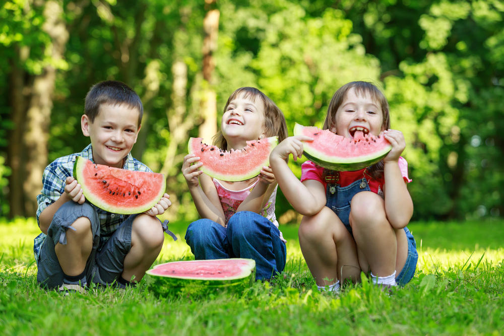 Kids enjoying watermelon at the picnic area